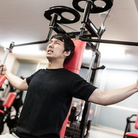 マシンフライで大胸筋を鍛えるトレーニング中の男性の写真