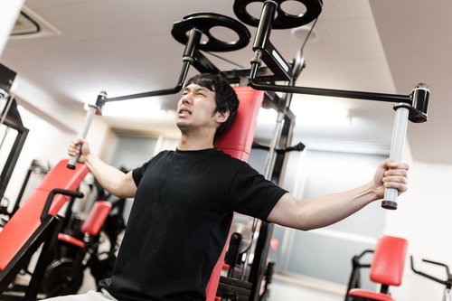 マシンフライで大胸筋を鍛えるトレーニング中の男性