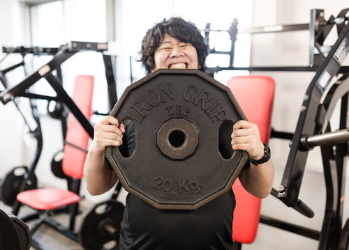 でっかい、20キロのウェイトを両手で掲げる男性