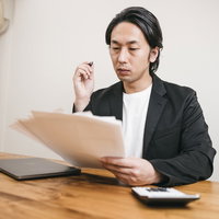 書類に目を通す面接官の男性、採用選考の審査の場面の写真