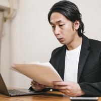 口をすぼめて書類を確認する男性採用担当者の写真