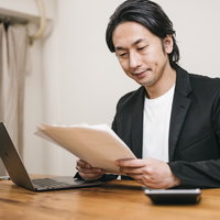 書類に目を落とす審査員の男性が真剣に検討している採用面接の写真