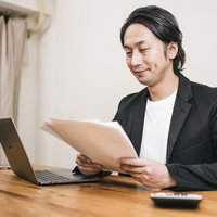深夜まで書類整理をするフリーランスの男性の写真