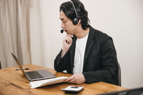 ヘッドセットを装着してリモートワークする男性