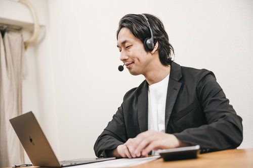 ヘッドセットを着用して自宅からリモートワークするオペレーター男性