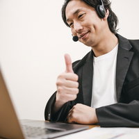 ヘッドセットを着用してグッジョブのポーズを取る男性の写真