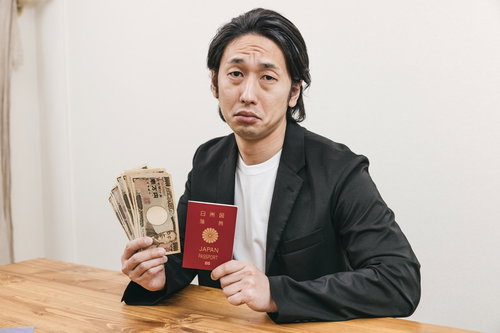 札束とパスポートを手に持つスーツ姿の男性