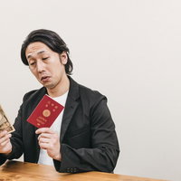 紙幣と赤いパスポートを持った太々しい態度の男性の写真