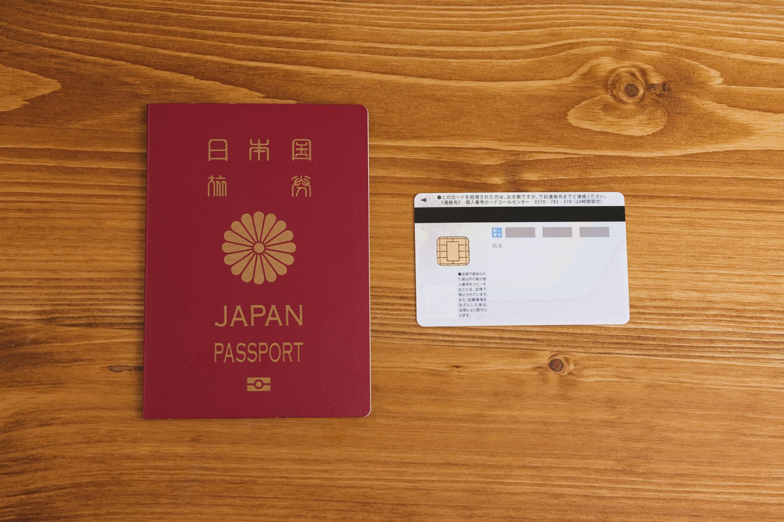 木目のテーブルに並んで置かれた日本のパスポートとマイナンバーカード