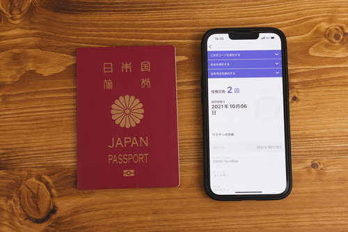 旅券とワクチンパスポートアプリ表示のスマホを並べて撮影