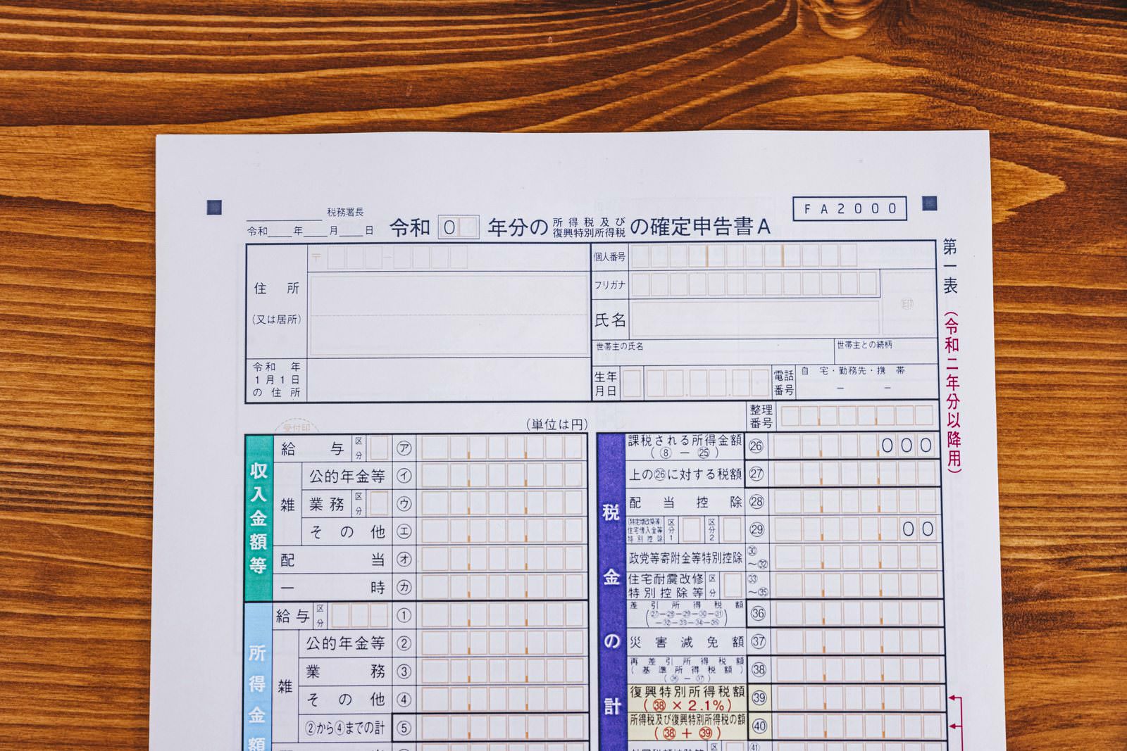 木製の机の上に置かれた白い確定申告書と青いペン