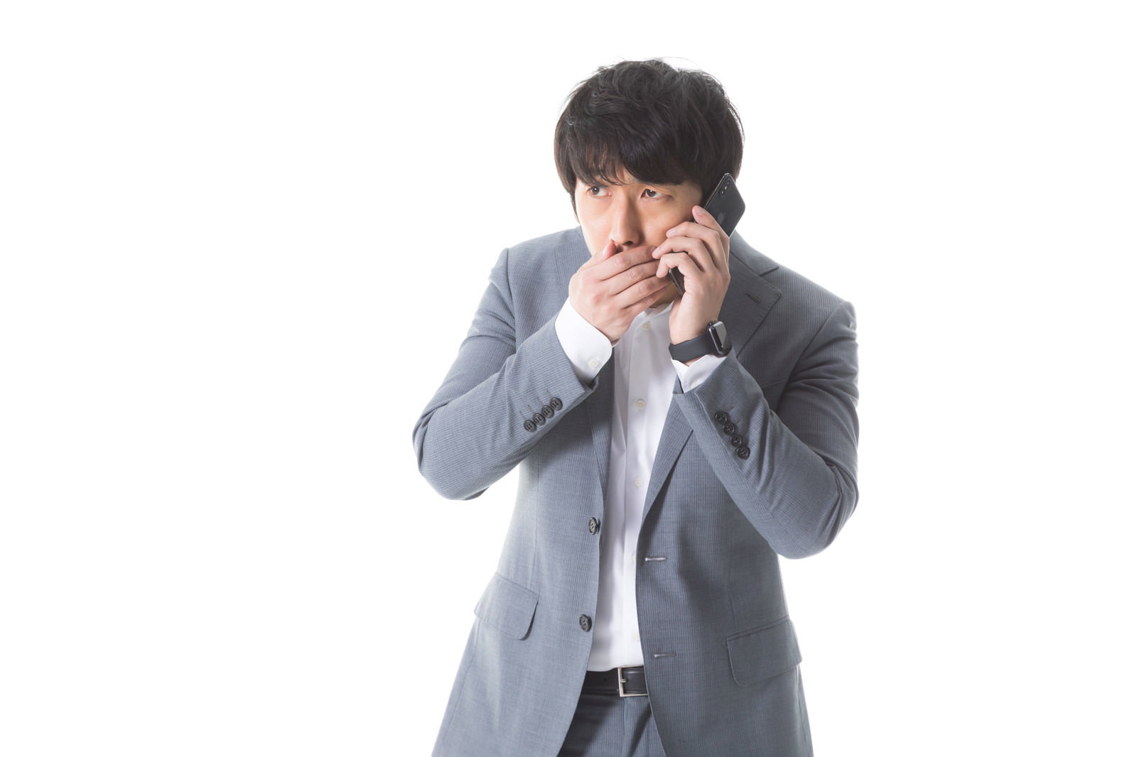 片手で顔を覆いながら電話をする、グレーのスーツ姿の男性［モデル：大川竜弥］