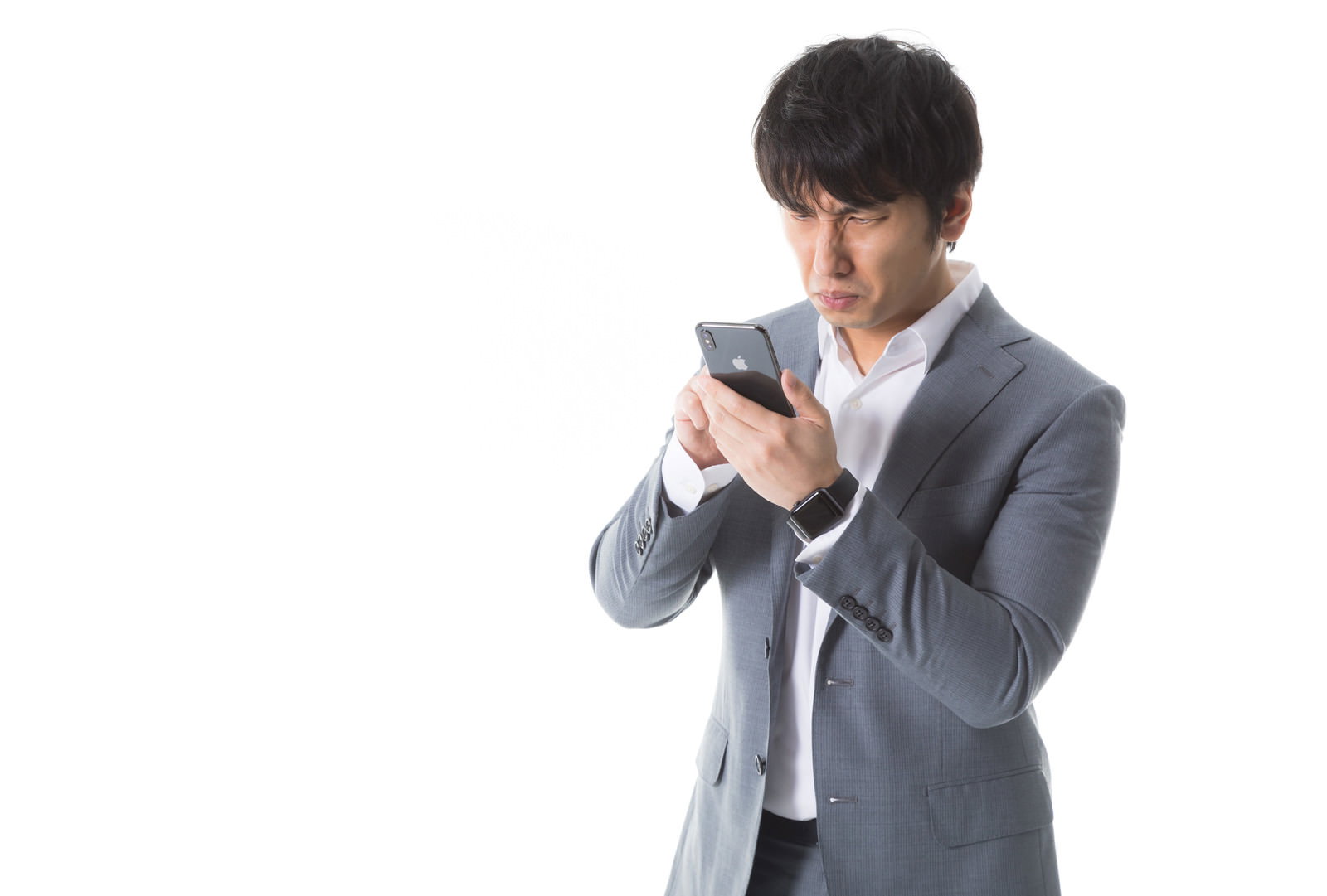 スマートフォンを見て困った表情を浮かべるグレーのスーツ姿の男性［モデル：大川竜弥］