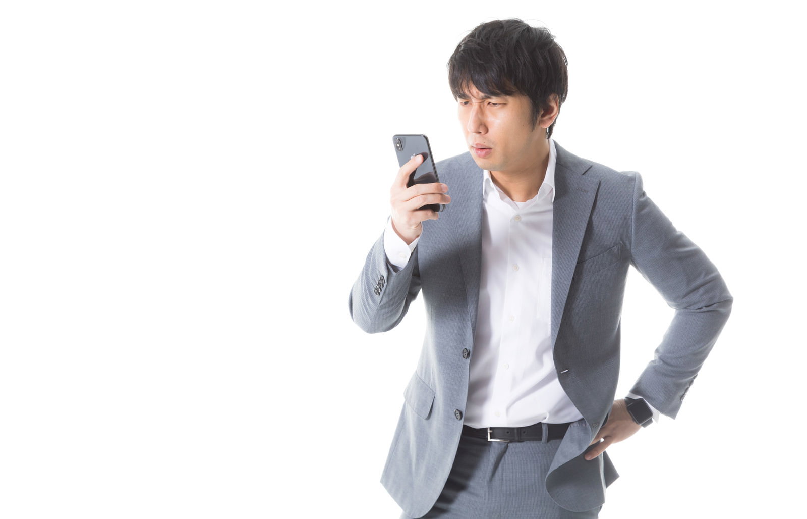 スマートフォンを見て困った表情を浮かべるグレーのスーツを着た男性［モデル：大川竜弥］