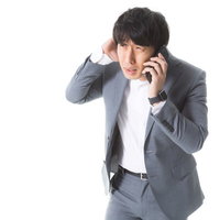 クライアントに納期の遅れを謝罪する広告代理店社員男性の写真