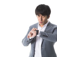 【緊急】と書かれたメールの通知に怯えるスーツ姿の男性の写真