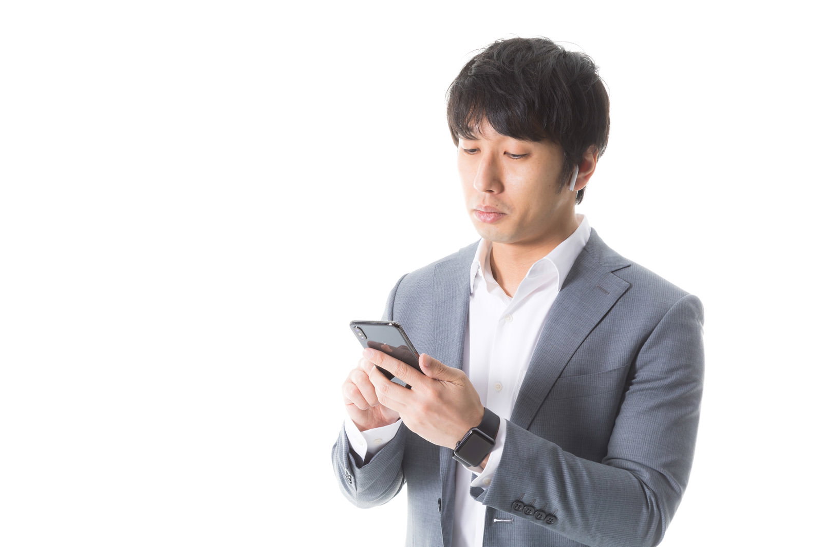 グレースーツの男性がスマートフォンを真剣に操作している様子［モデル：大川竜弥］