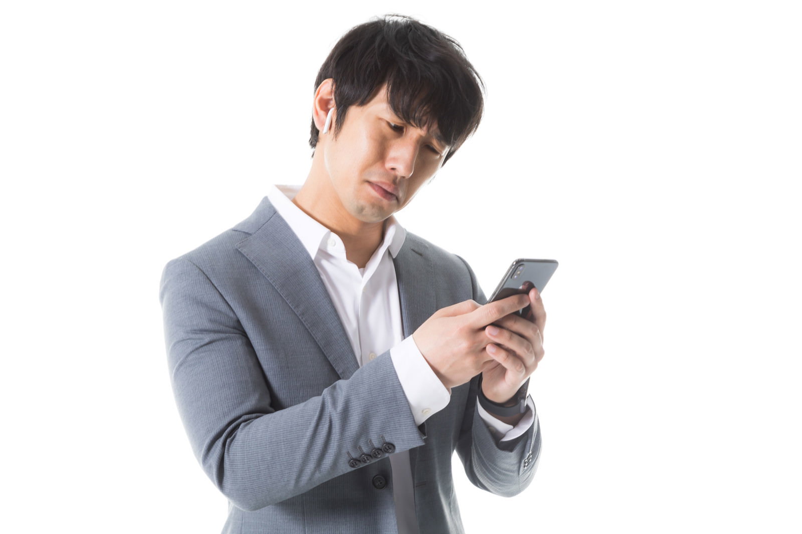 グレーのスーツを着た男性がスマートフォンを見て困った表情をしている［モデル：大川竜弥］