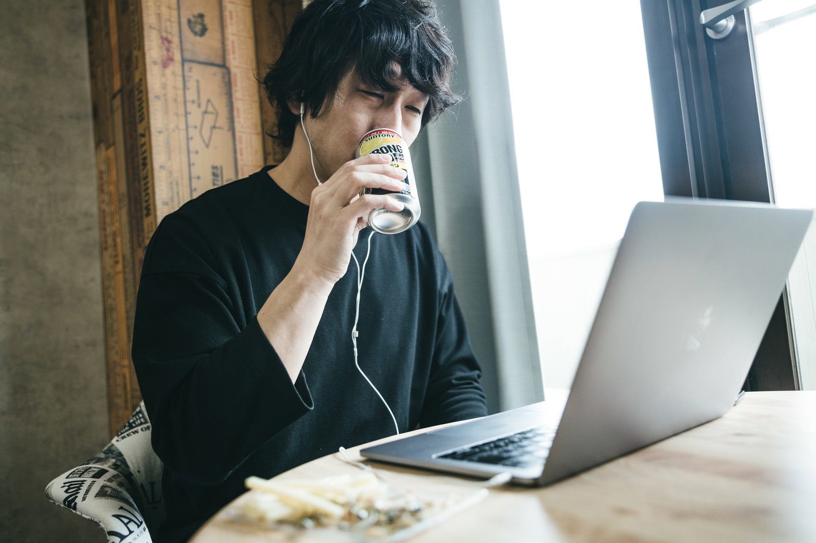 パソコンの前で缶のお酒を持ちながらリモート飲み会に参加している男性［モデル：大川竜弥］