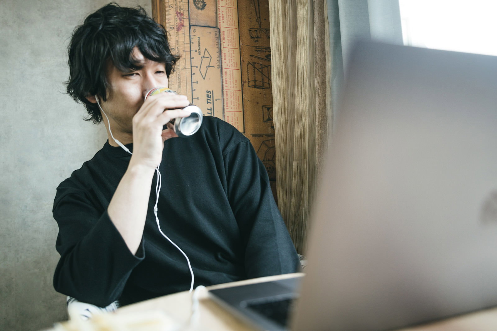 缶チューハイを手に持ちながらパソコンの前に座る男性［モデル：大川竜弥］