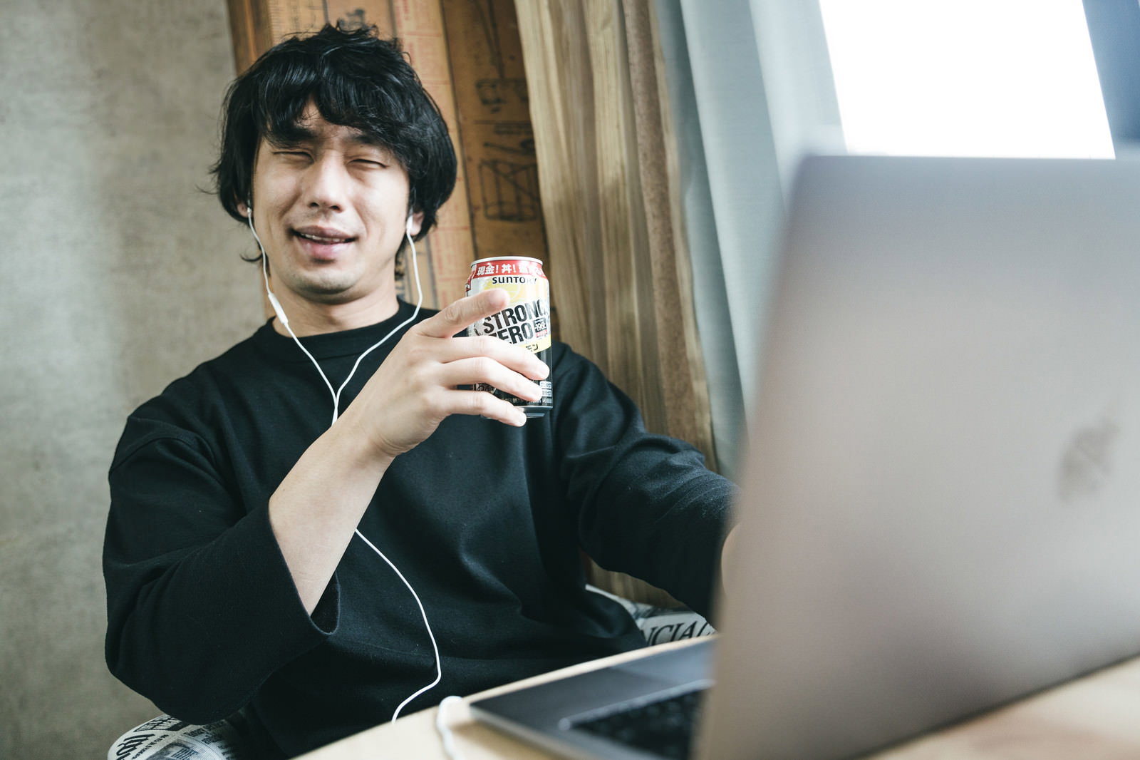 黒い服を着た男性がお酒を手に持ち指差しポーズをする様子［モデル：大川竜弥］