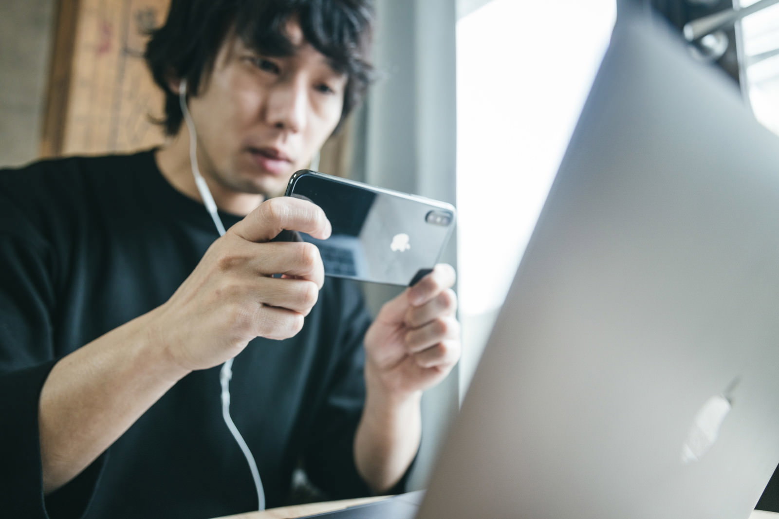 スマートフォンでノートパソコンの画面を撮影している男性［モデル：大川竜弥］
