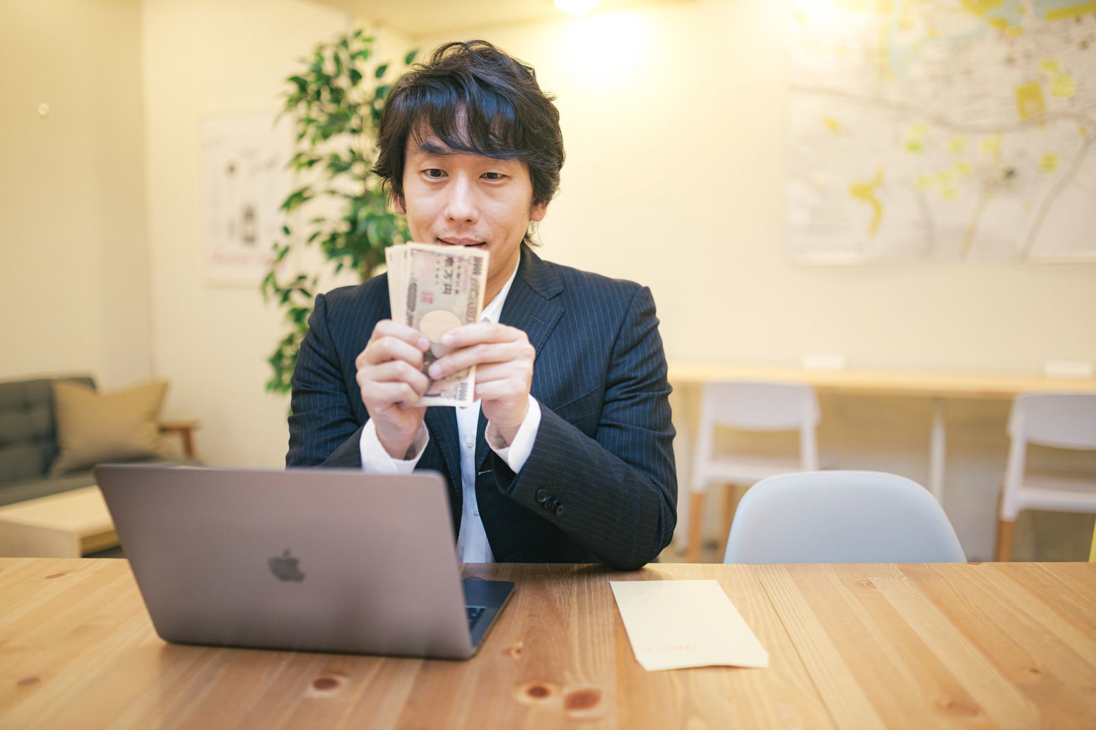 一万円札を両手に持ちカメラに微笑む男性［モデル：大川竜弥］