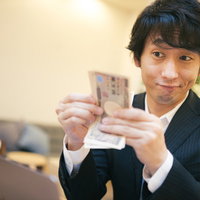 10万円ゲットだぜ！現金を手にしてにやける男性の写真