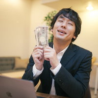 支給された10万円の現金を手にして喜ぶ会社員男性の写真