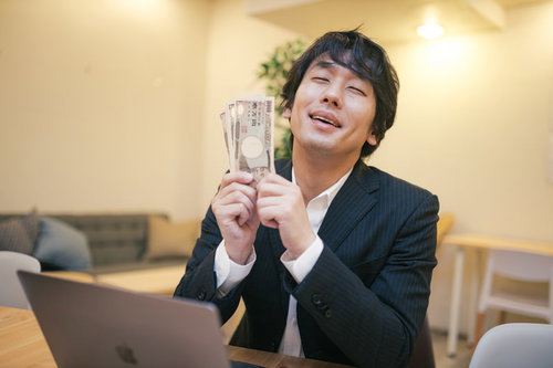 支給された10万円の現金を手にして喜ぶ会社員男性