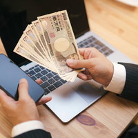 10万円の現金とスマートフォン、ノートパソコンの写真