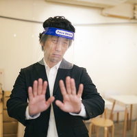 「密です！」フェイスシールドで接触拒否するビジネスマンの写真