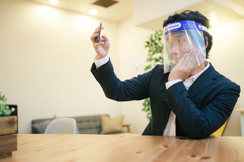 フェイスシールドを着用して自撮りする男性