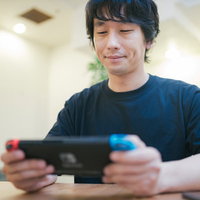 自宅で人気の携帯ゲーム機に熱中する男性ゲーマーの写真