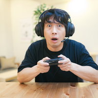 黒いヘッドセットを装着してオンラインゲームに熱中する男性の写真