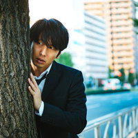 浮気調査で尾行中の探偵が木陰に身を隠して張り込むの写真