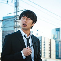 捜査に行き詰まり途方に暮れる刑事男性、ビル群の前で頭を抱えるの写真