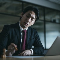 判子を押しに夜遅くまで残業する会社役員男性の写真