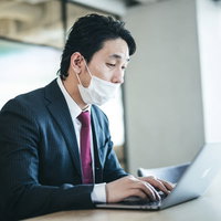 息苦しくて鼻出しマスクで作業する会社員男性の写真