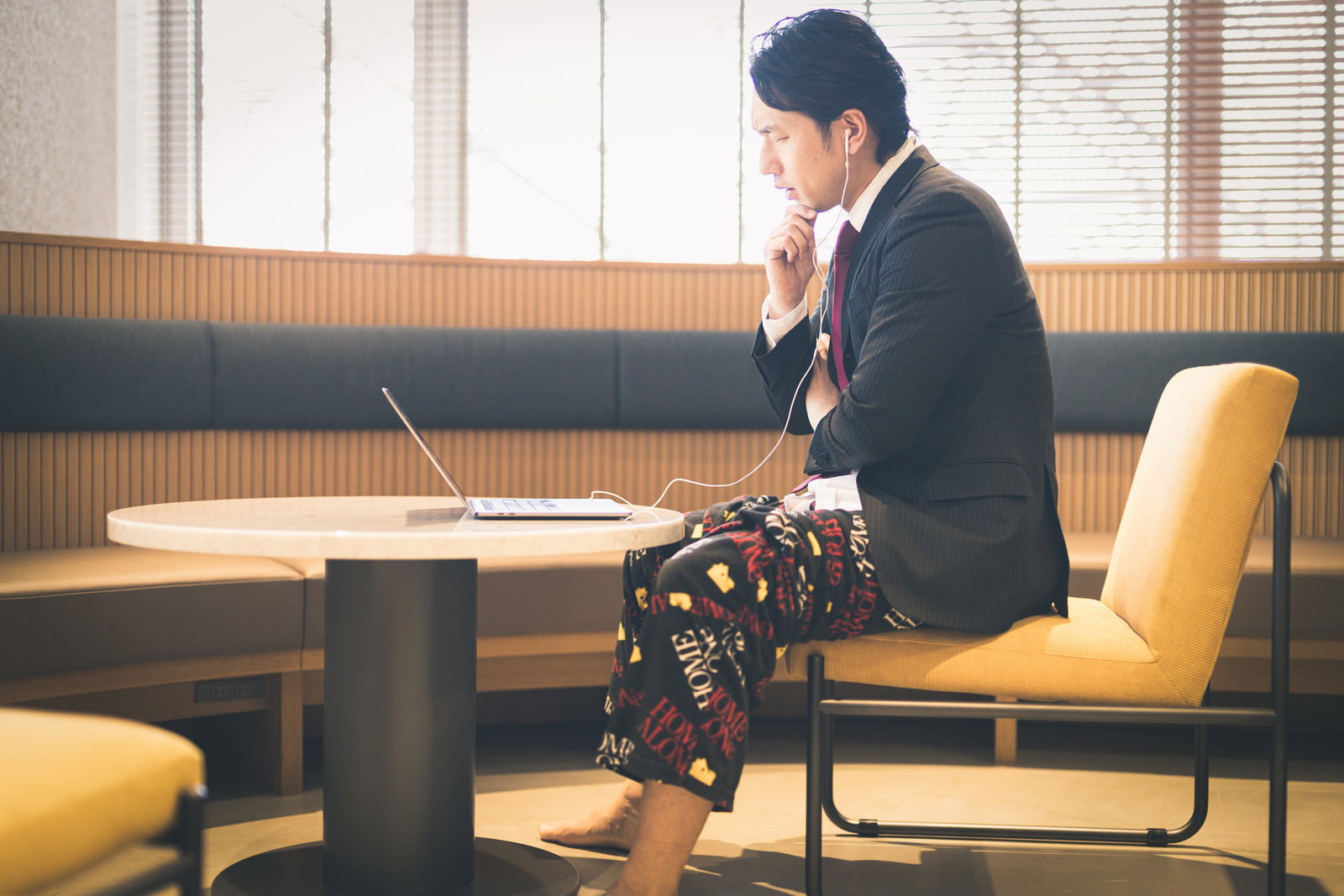 オンライン会議中の男性、上半身スーツ下半身パジャマでパソコンに向かう様子［モデル：大川竜弥］