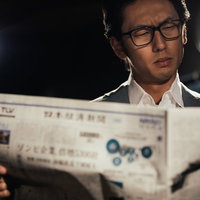 経済新聞を広げて読むビジネスマンの写真