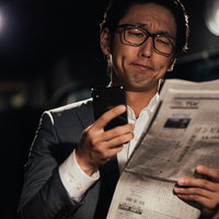 紙面と電子版を同時にチェックするビジネスマンの写真