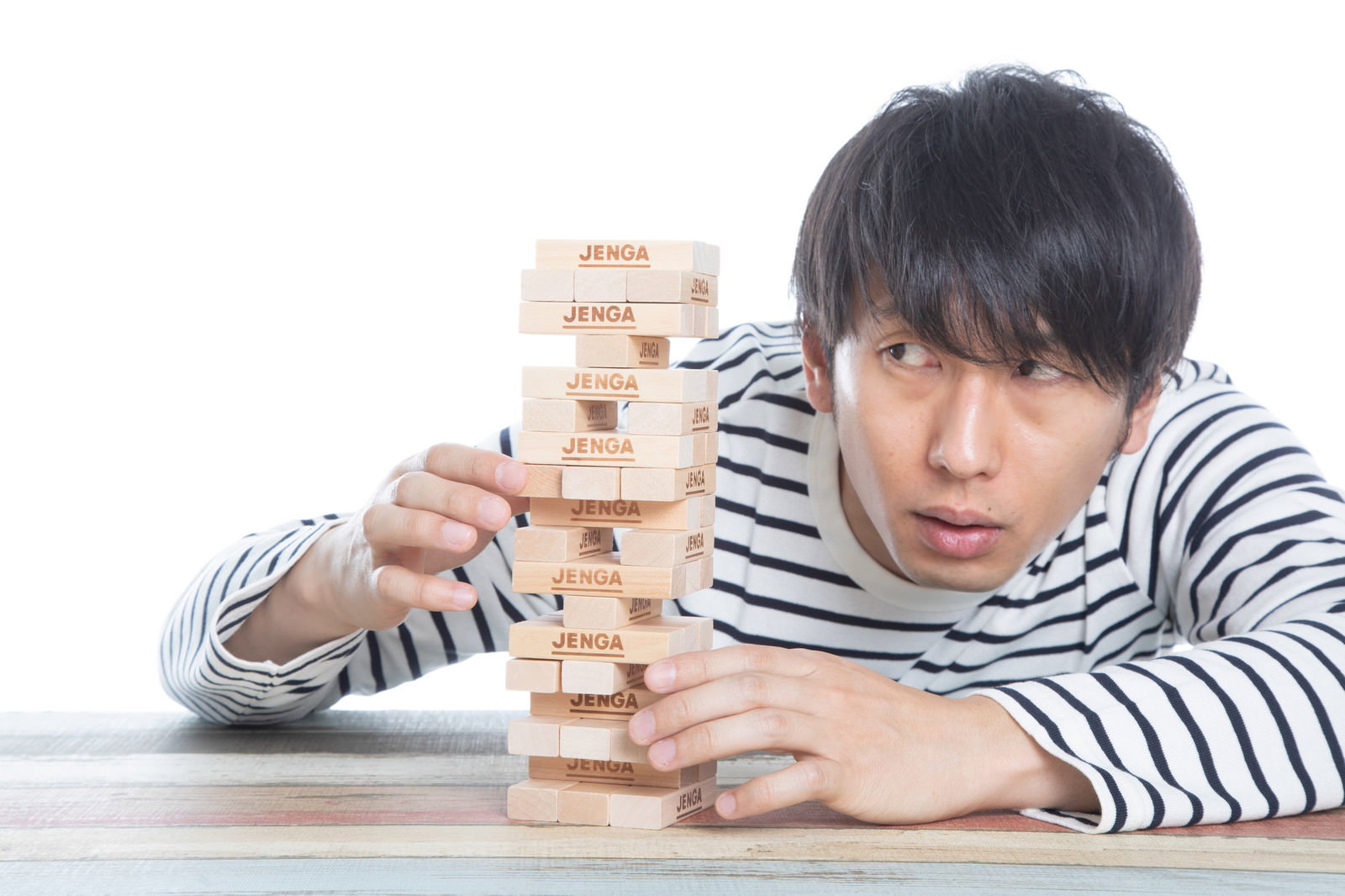 テーブルでジェンガゲームをする男性［モデル：大川竜弥］