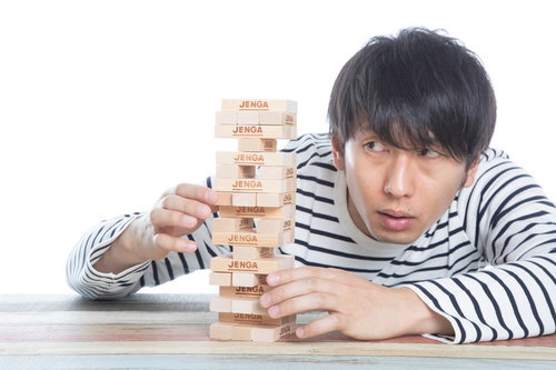 ひとりでジェンガをする男性が積み木を取り出す瞬間