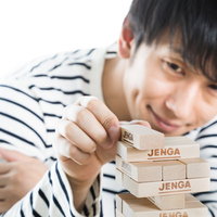 ジェンガの積み木を引き抜く男性の写真