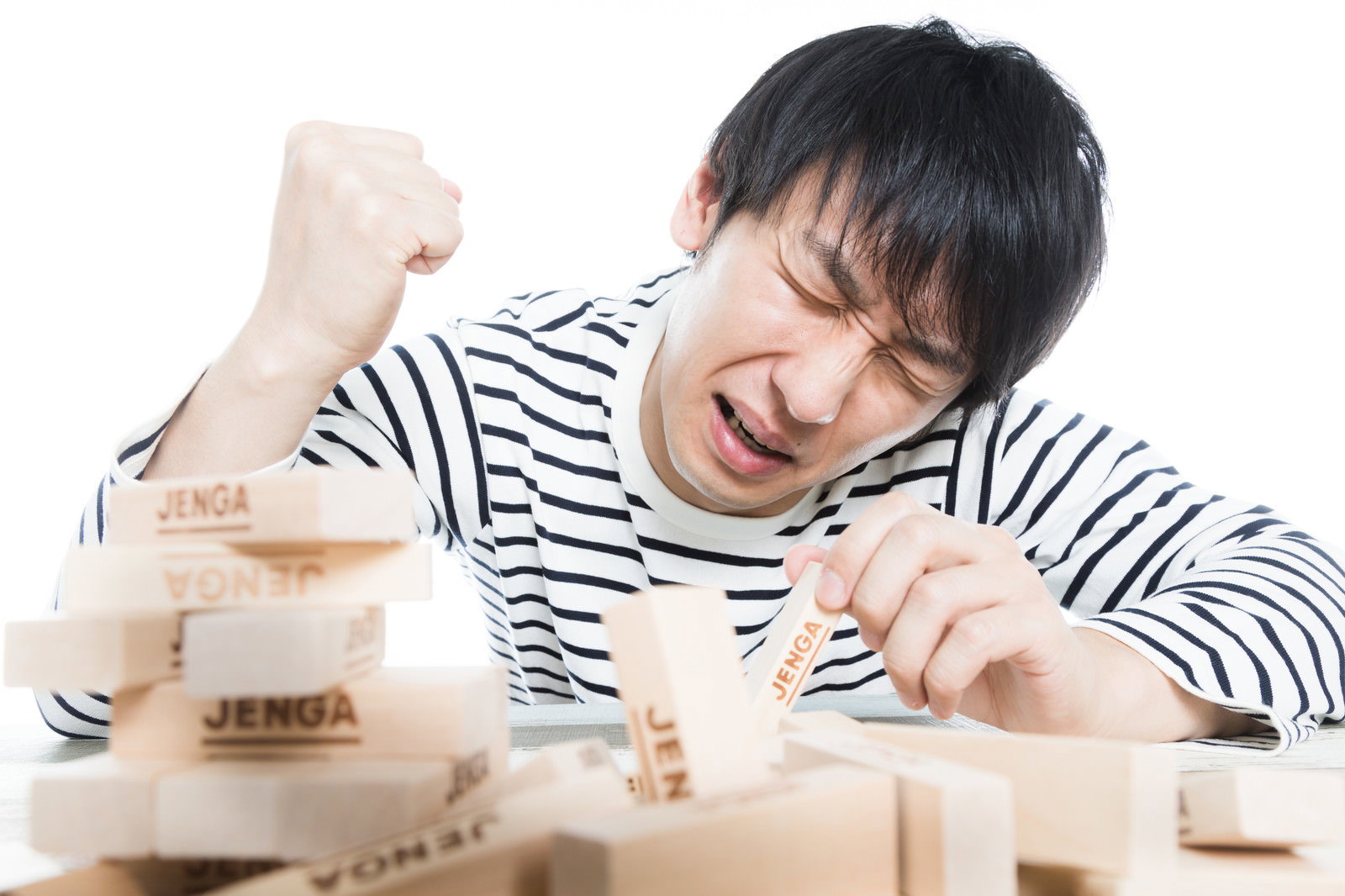ジェンガが崩れて手で顔を覆い泣いている男性［モデル：大川竜弥］