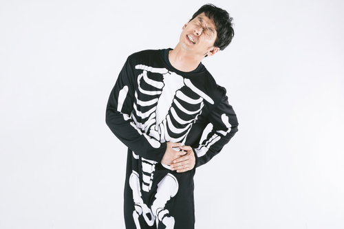 左脇腹の痛みで苦しむスケルトンスーツの男性