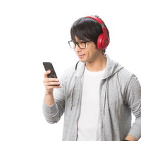 スマホでワイヤレスヘッドホンを操作する男性の写真