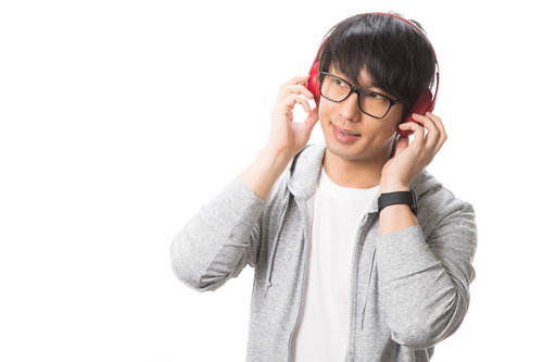 ヘッドフォンで音楽を楽しむグレーパーカーの男性