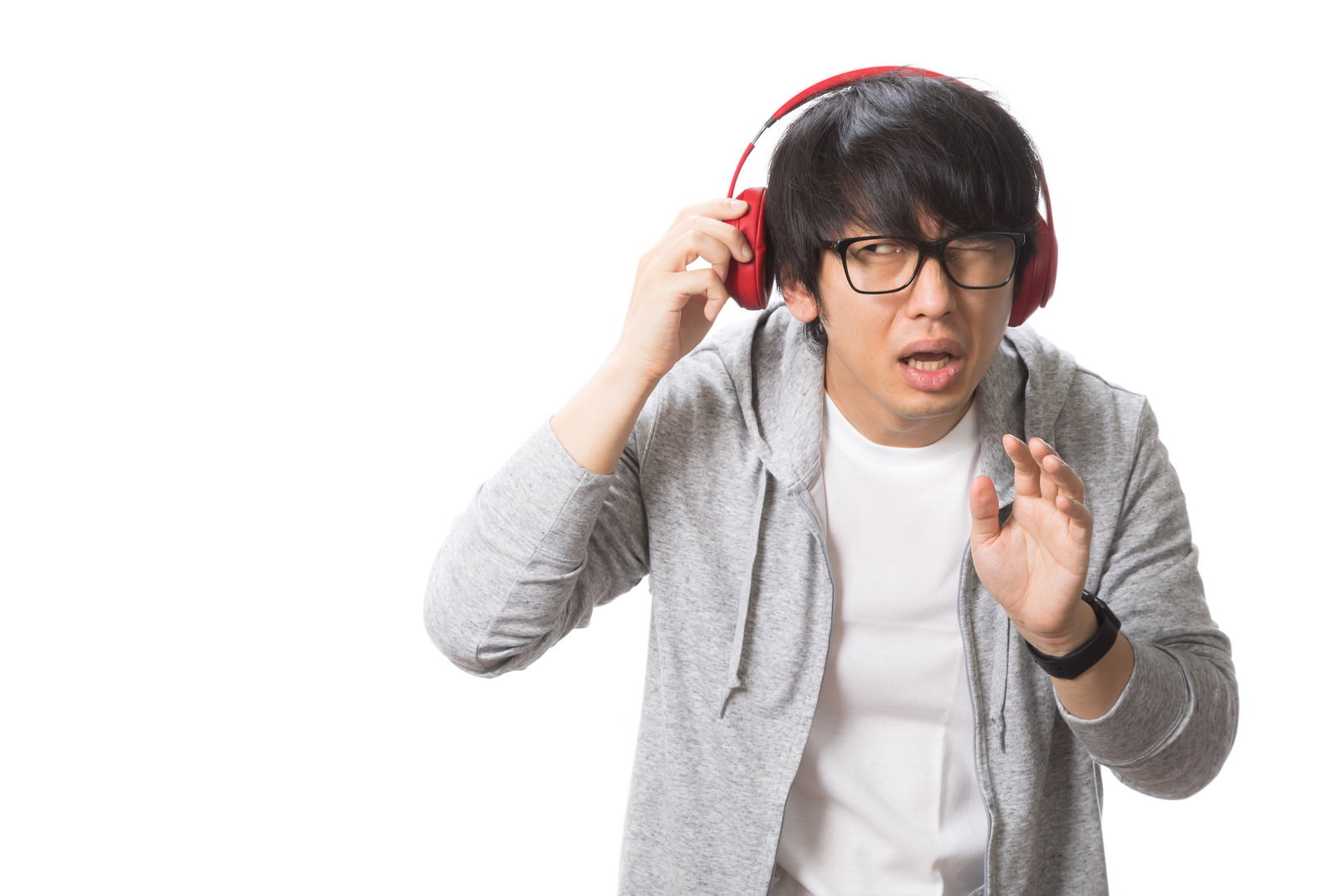 グレーのパーカーを着てヘッドホンをした男性が片手で謝罪のポーズを取っている様子［モデル：大川竜弥］